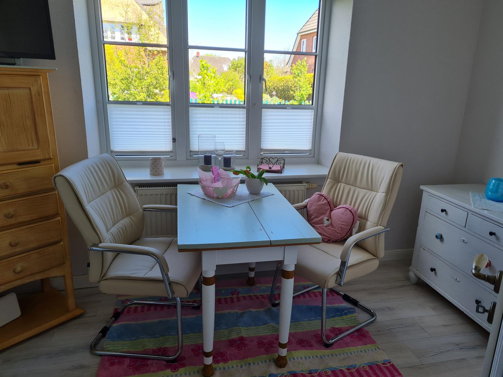 Essbereich mit Tisch, zwei Stühlen und Blick auf Garten.