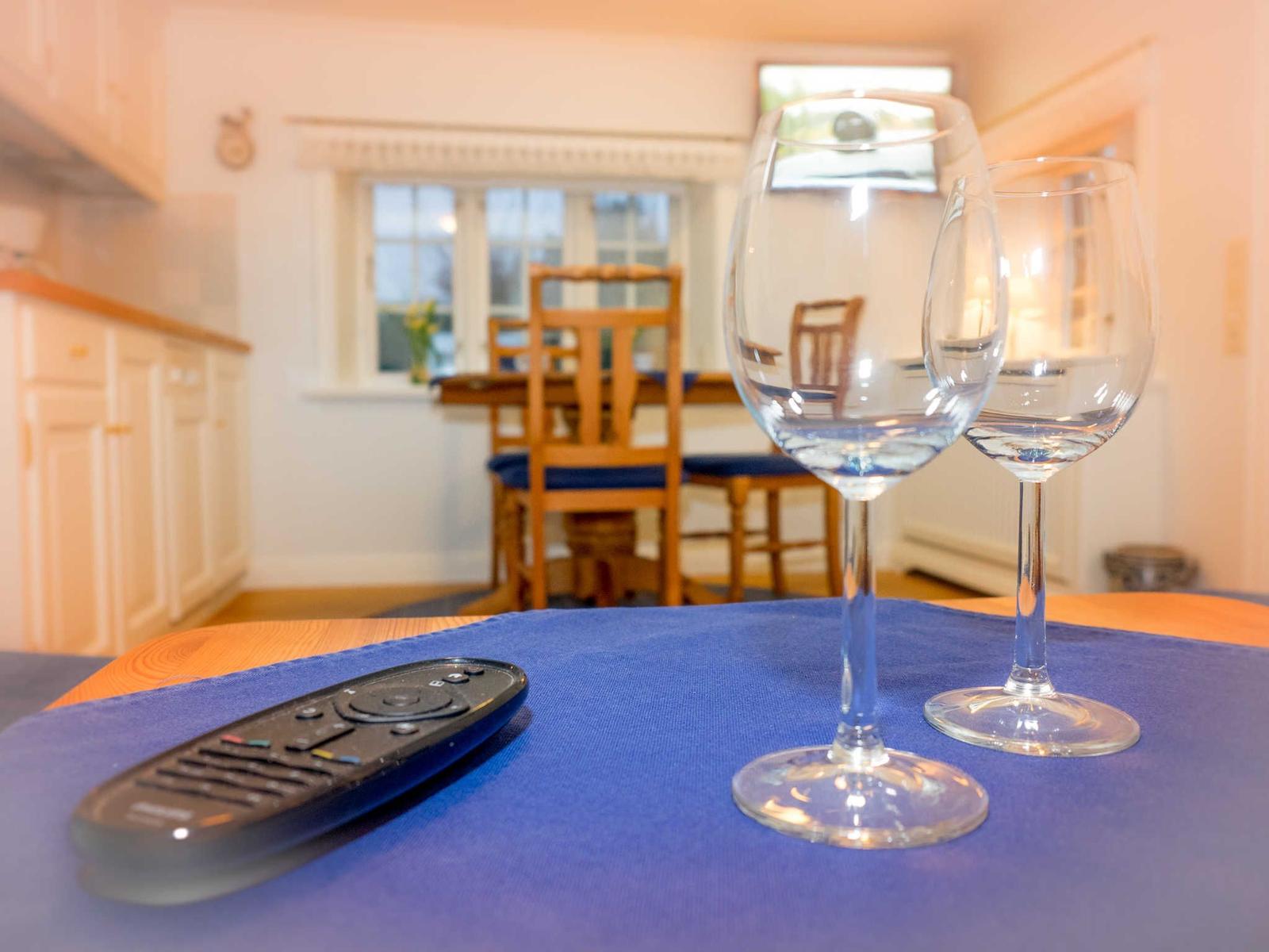 Wooden table with chairs, a blue runner and a view to the kitchen.