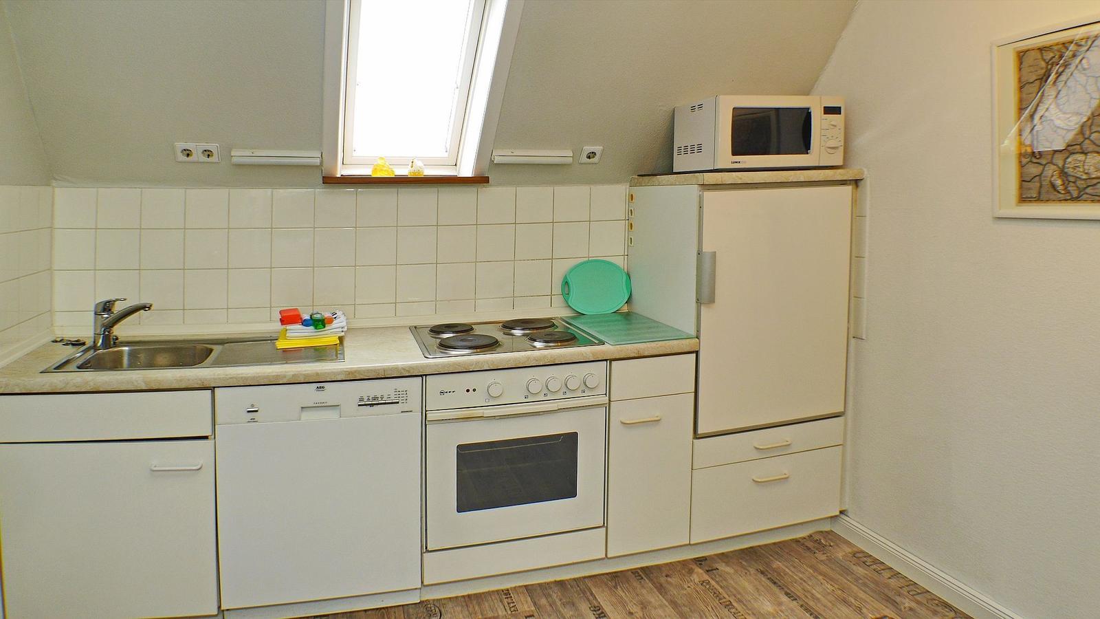 Küche mit Spüle, Herd, Geschirrspüler, Kühlschrank und Dachfenster.