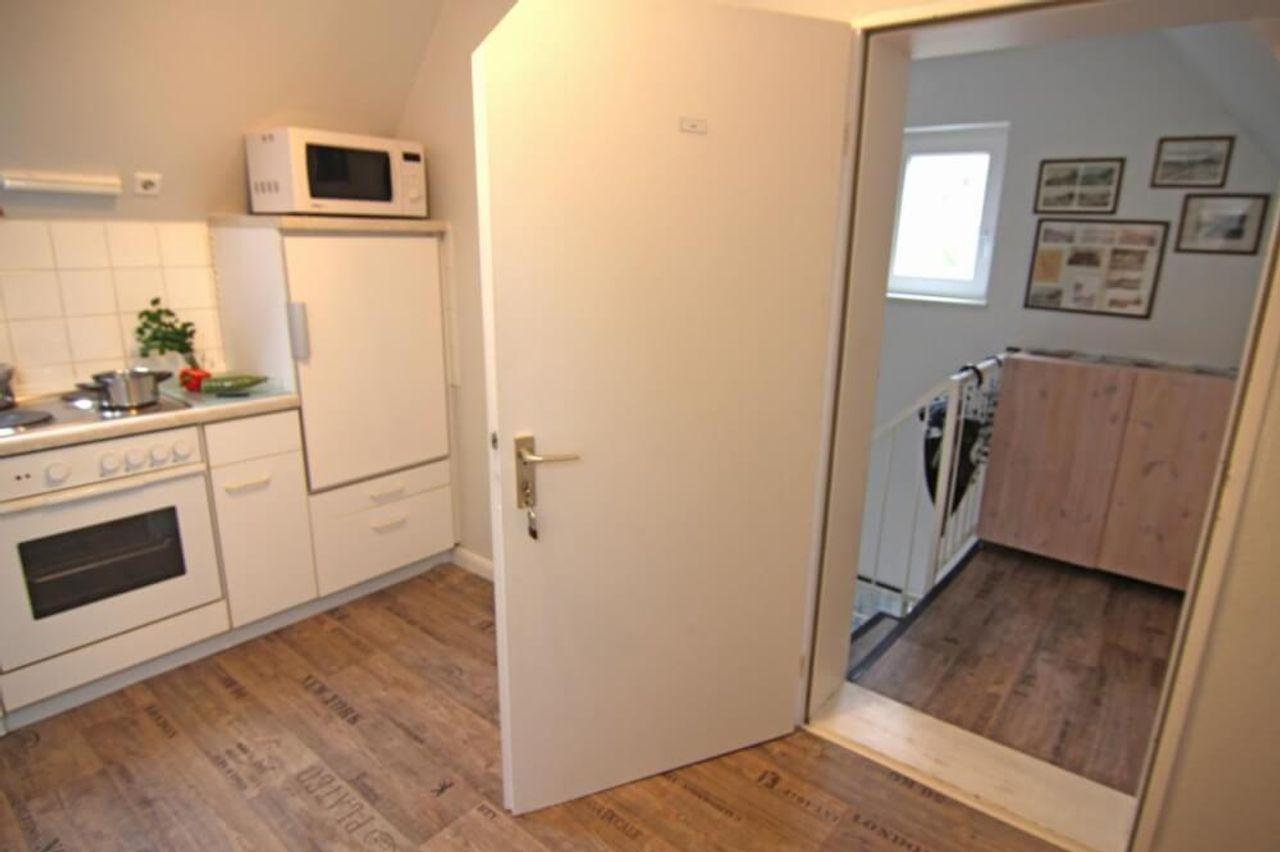 Küche mit Herd, Mikrowelle, Kühlschrank und Blick zur Treppe.