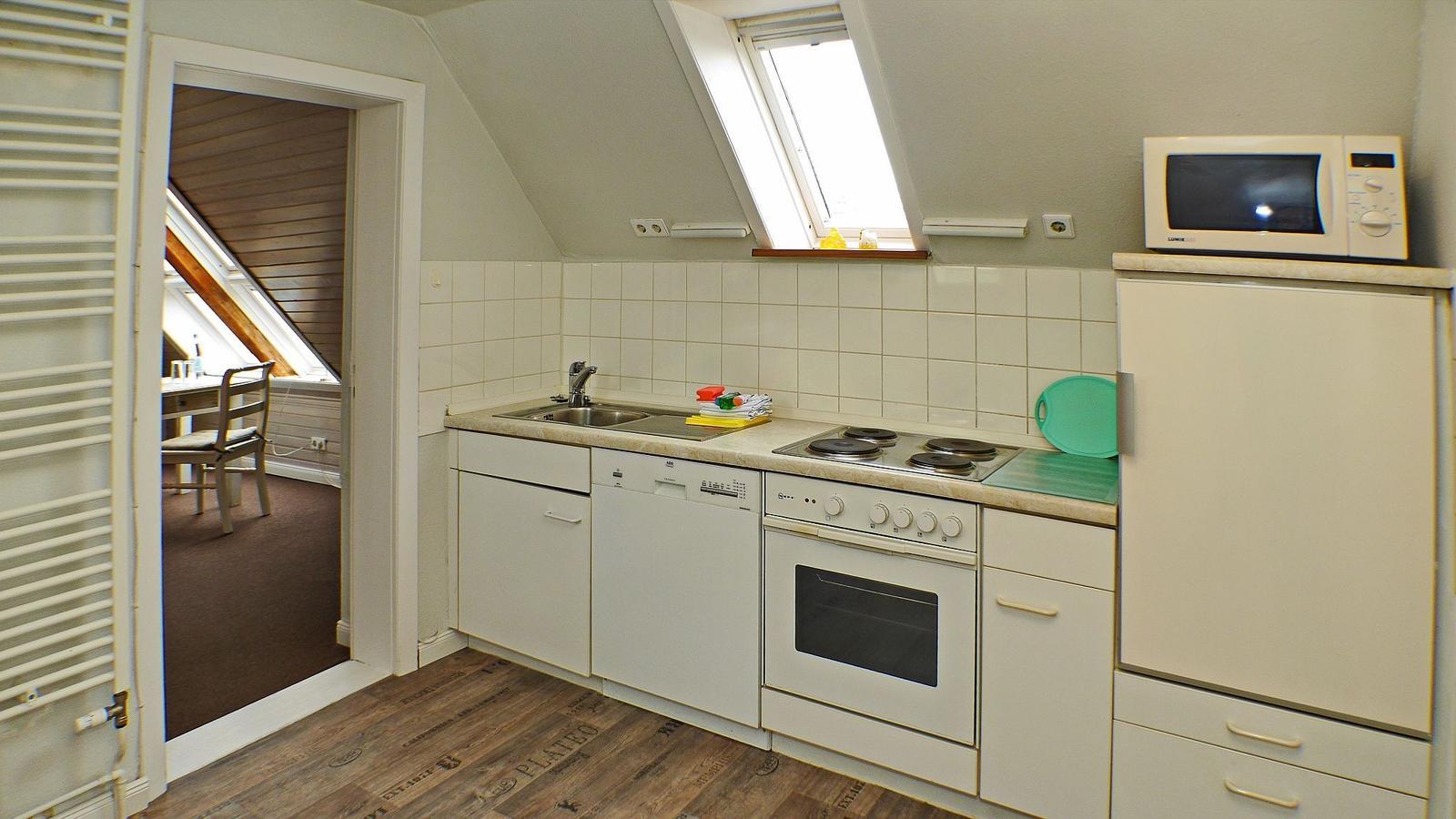 Küche mit Herd, Spüle, Kühlschrank und Durchgang zum Essplatz.
