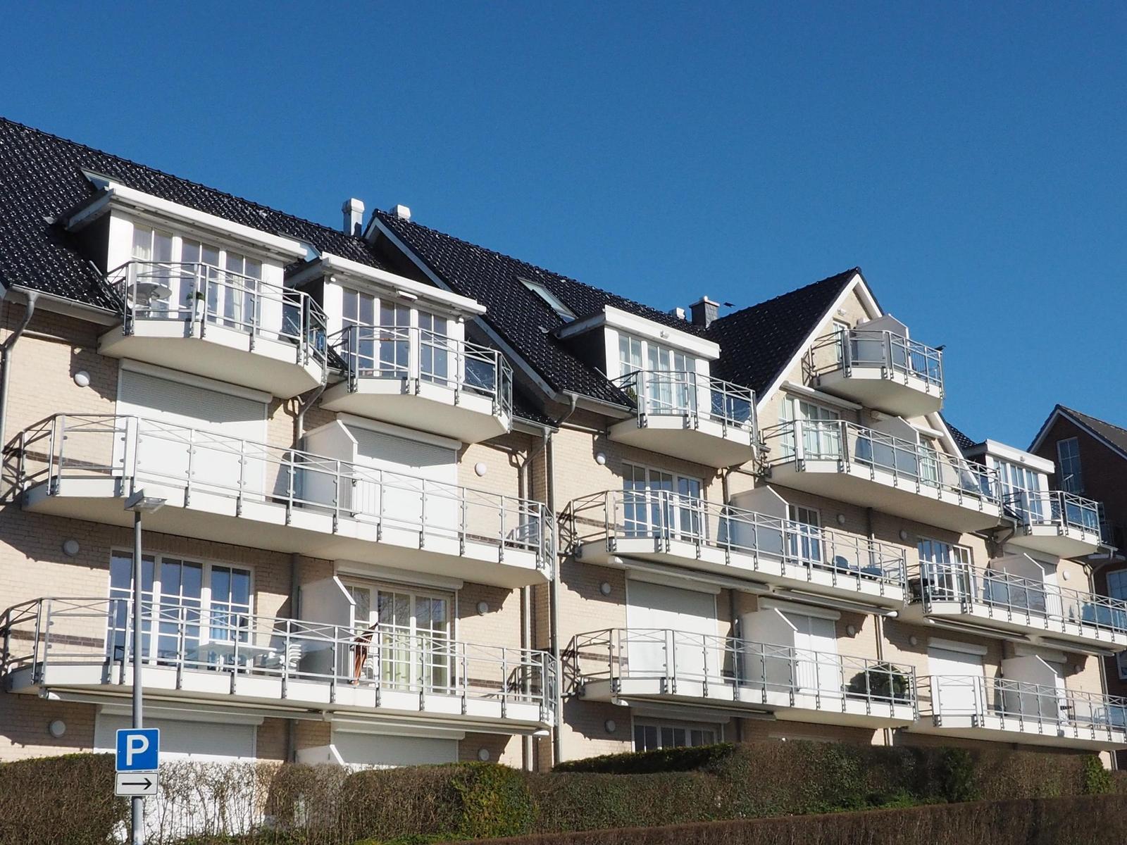 Mehrfamilienhaus mit Balkonen und Schiffsdekoration an der Fassade.