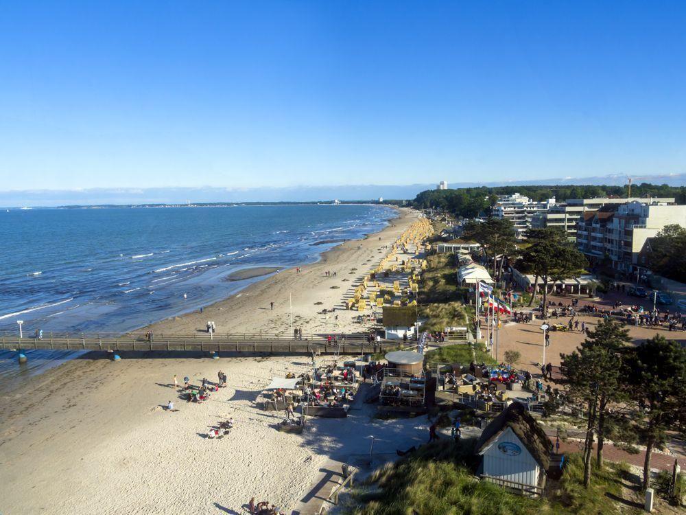 Pfad durch Grasland zum Strand mit See und blauem Himmel.