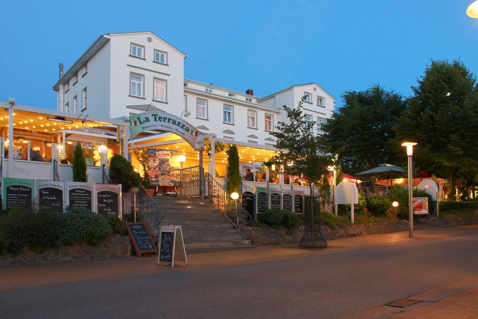 Strand mit Steg, Strandkörben und grüner Landschaft entlang des Meeres.
