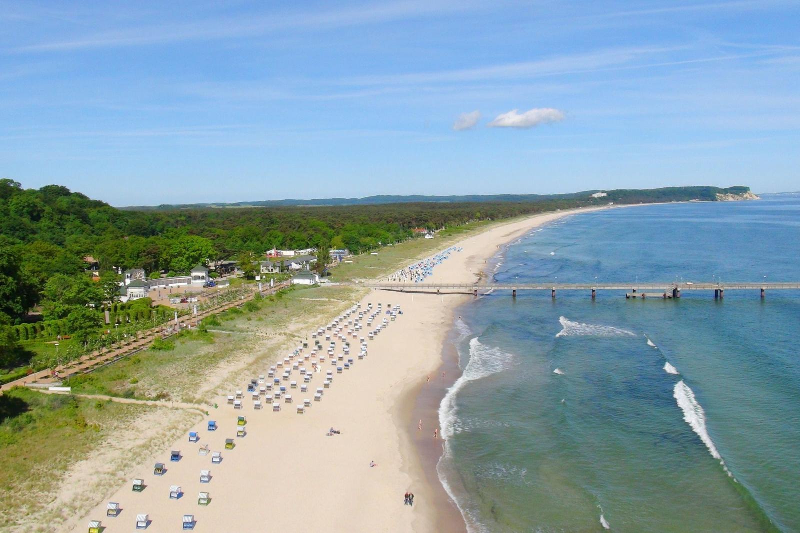 Willkommen im Ostseebad Göhren. Holzsteg mit Menschen und Flaggen über das Meer.