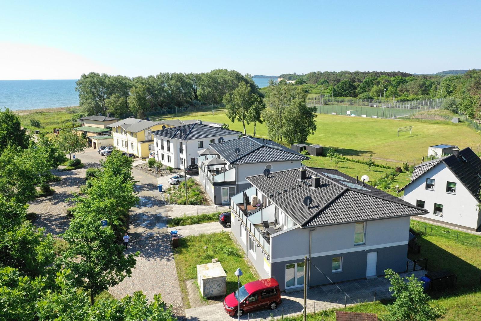 Zwei moderne Häuser mit Terrassen und umliegenden Grünflächen.