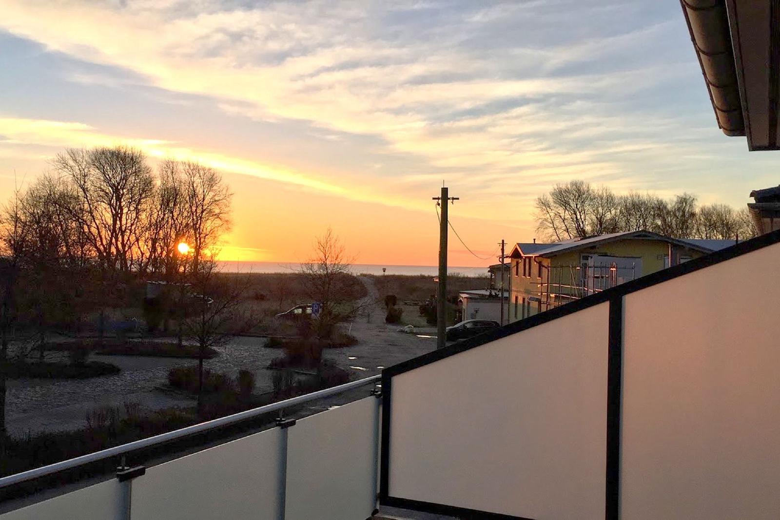 Strand mit sanften Wellen und Dünen im Sonnenlicht.