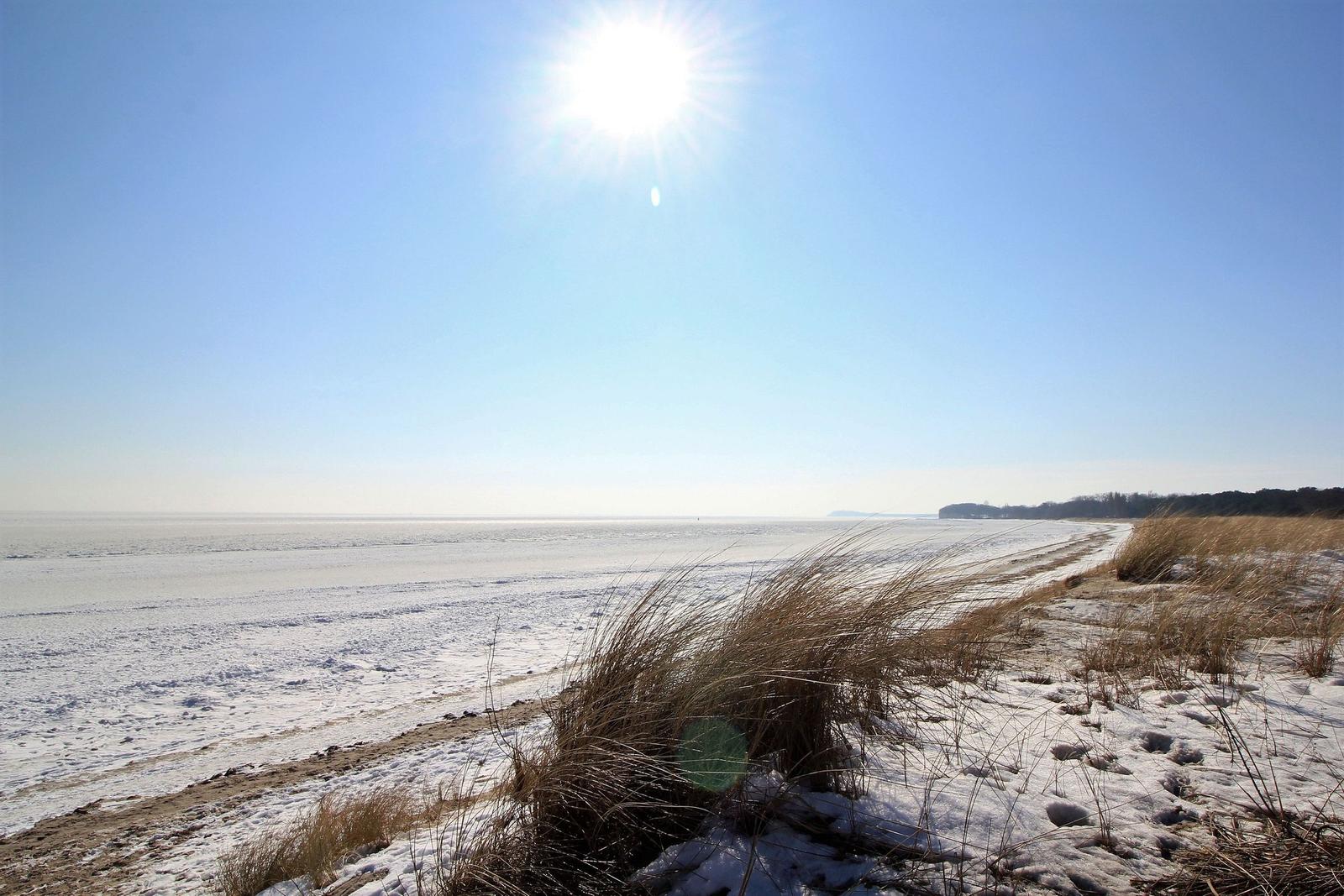 Schneebedeckter Boden unter strahlend blauem Himmel mit Sonne.