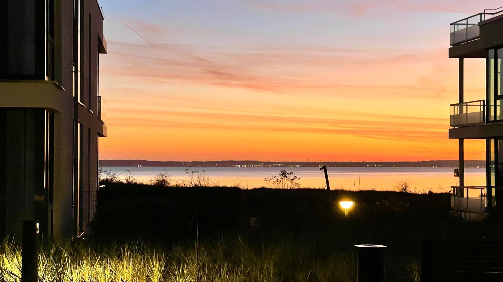 Blick auf See mit Segelbooten und Grünflächen im Vordergrund.