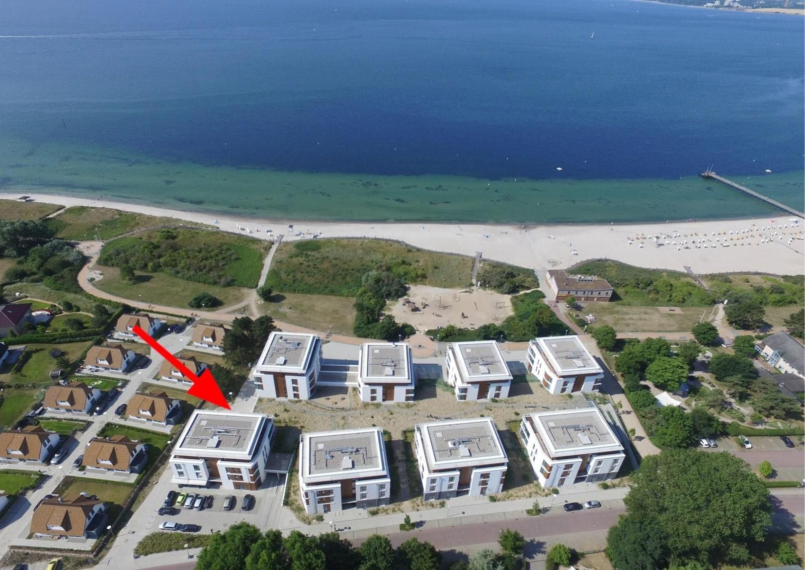 Meer mit Segelyacht unter bewölktem Himmel, rechts grüner Baum im Vordergrund.