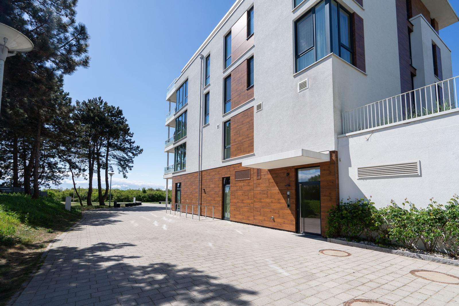 Moderne Mehrfamilienhäuser mit Balkonen und Grünanlagen unter blauem Himmel.