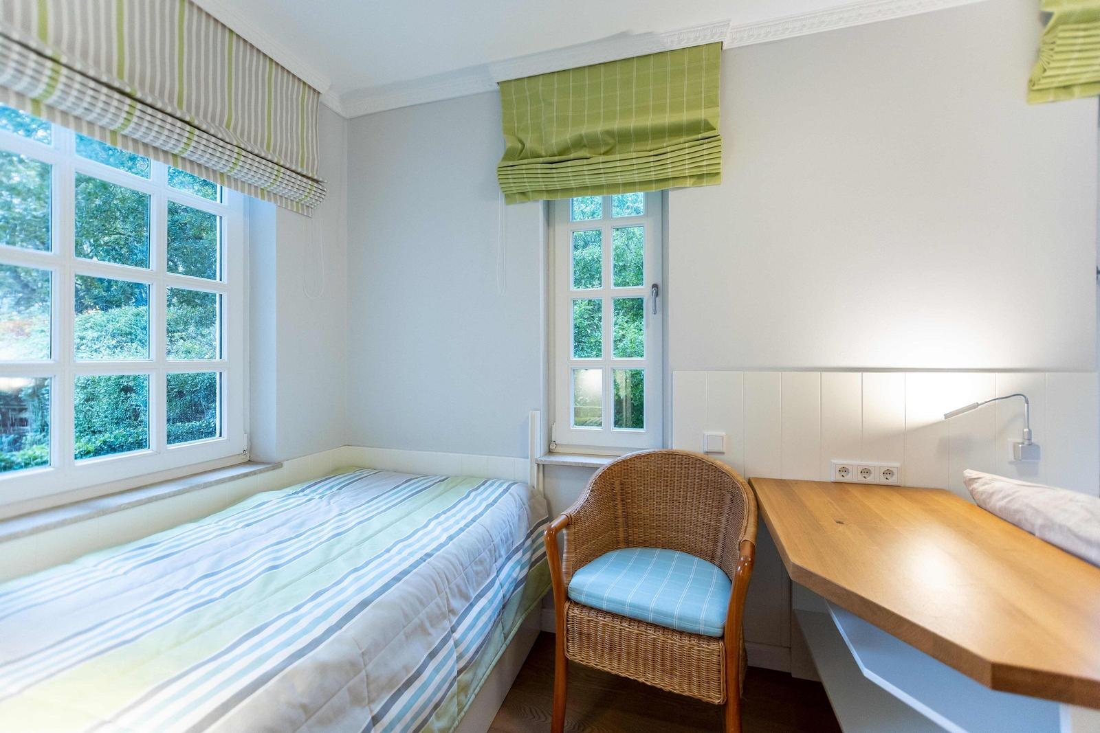 Zimmer mit zwei Betten, Fenstern und Holzboden.