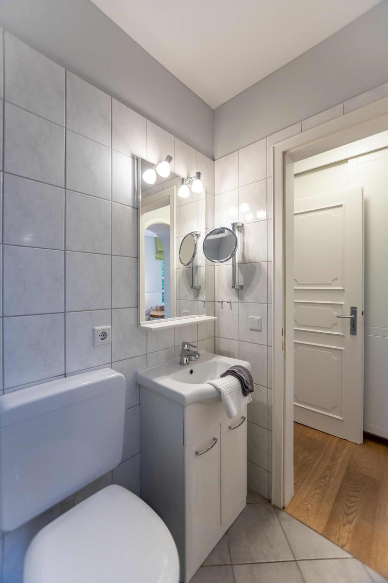 Badezimmer mit Dusche, Toilette und Waschbecken. Fenster mit Glassteinen.