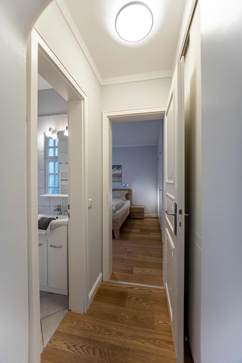 Schlafzimmer mit Doppelbett, weißen Schränken und Wandbild