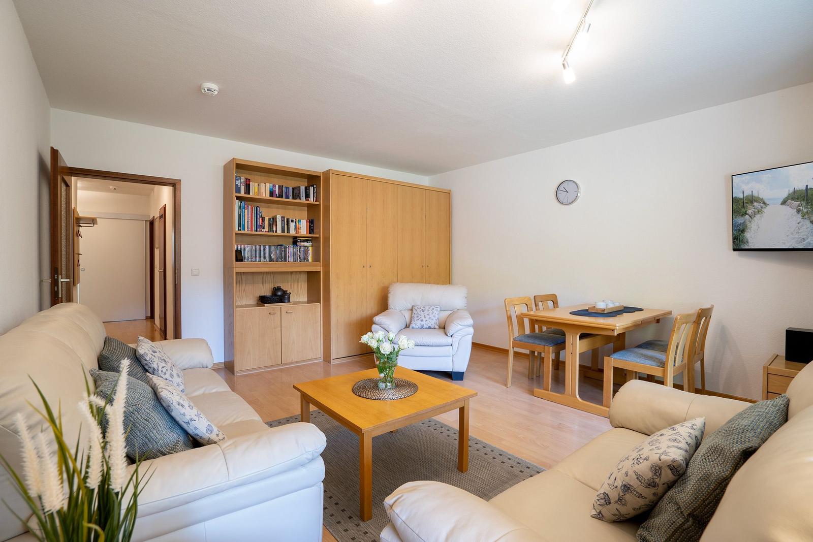 Wohn- und Essbereich mit Sofa, Couch, Tisch und Bücherregal.