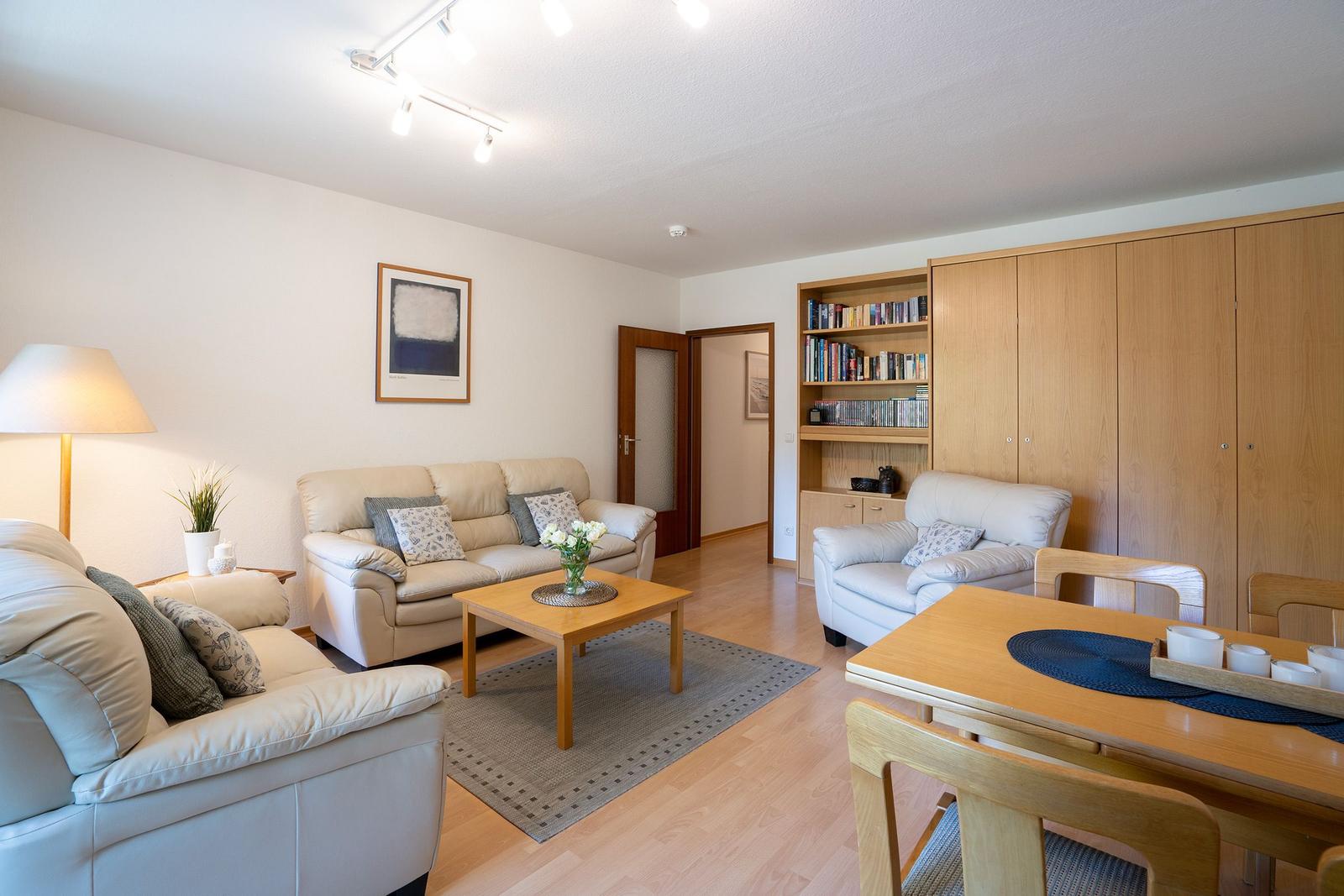 Wohn- und Essbereich mit Sofa, Sessel, Esstisch und Bücherregal.