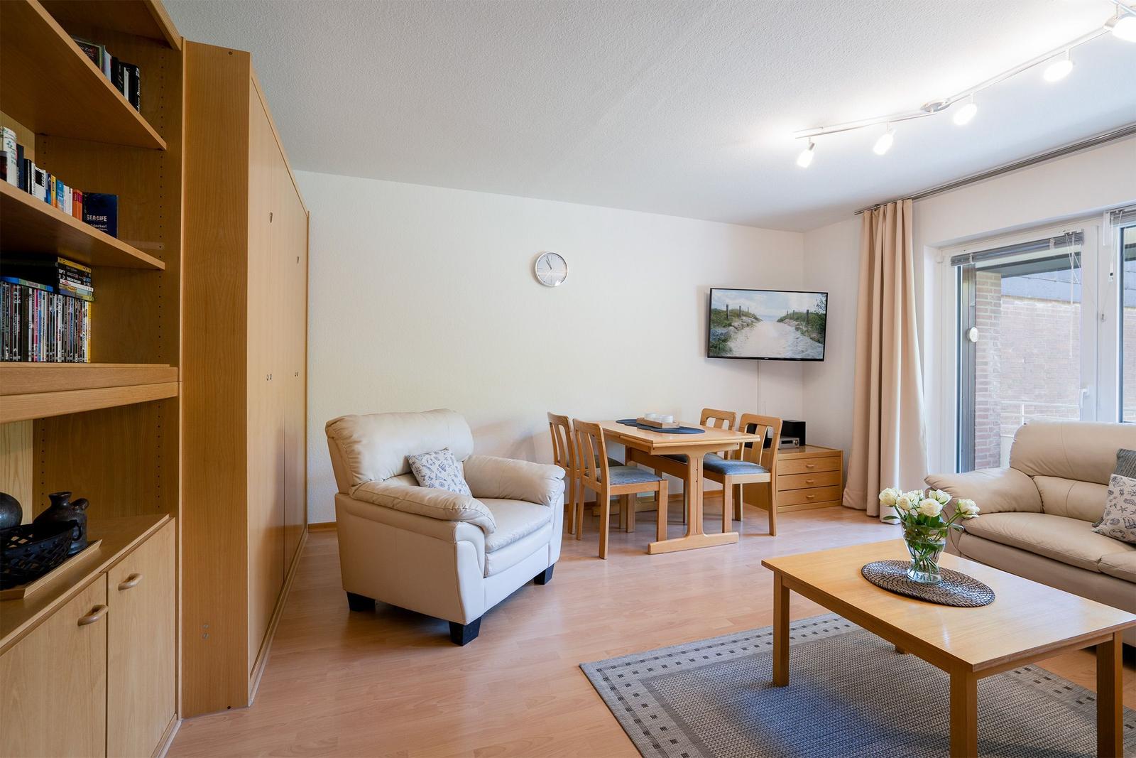 Wohn- und Essbereich mit Sofa, Esstisch, Fernseher und Balkontür.
