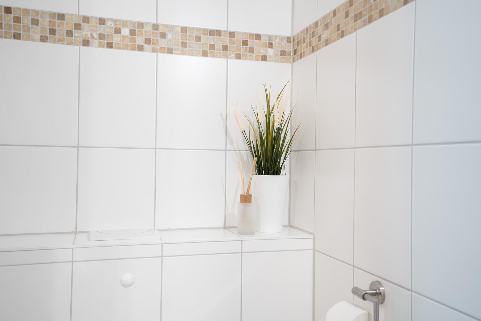 Badezimmer mit Dusche, Waschbecken und Sauna. Holztüren und Fliesenwand.