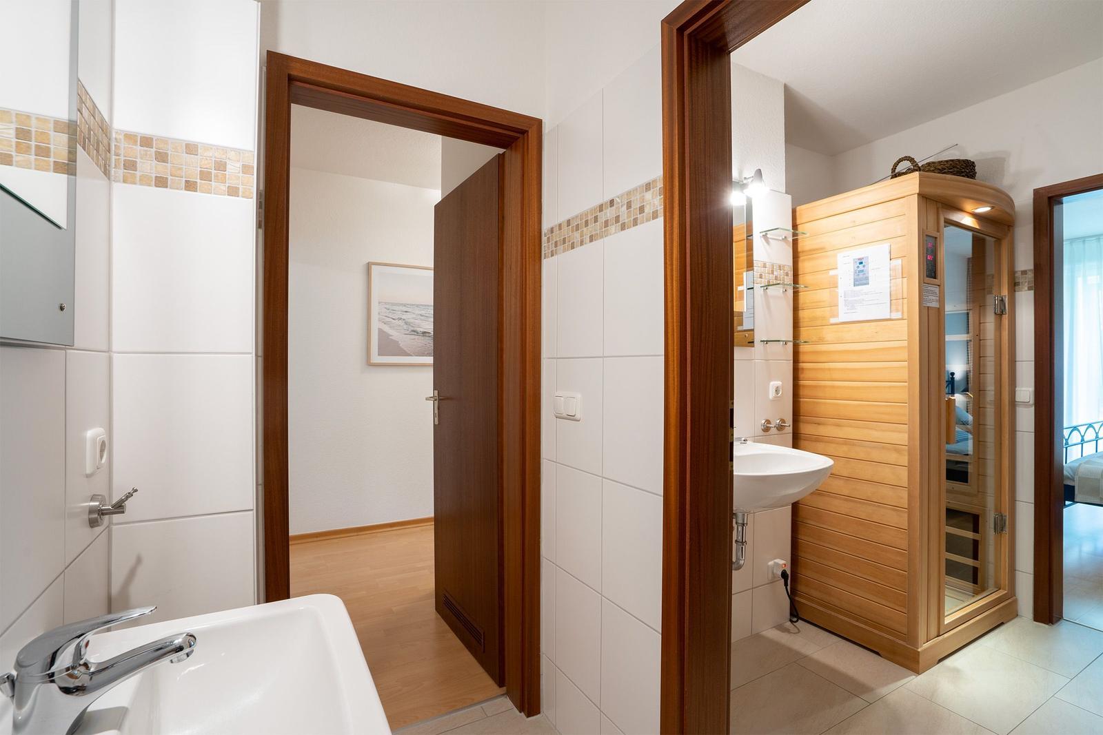 Schlafzimmer mit Bett und Sauna im Hintergrund.