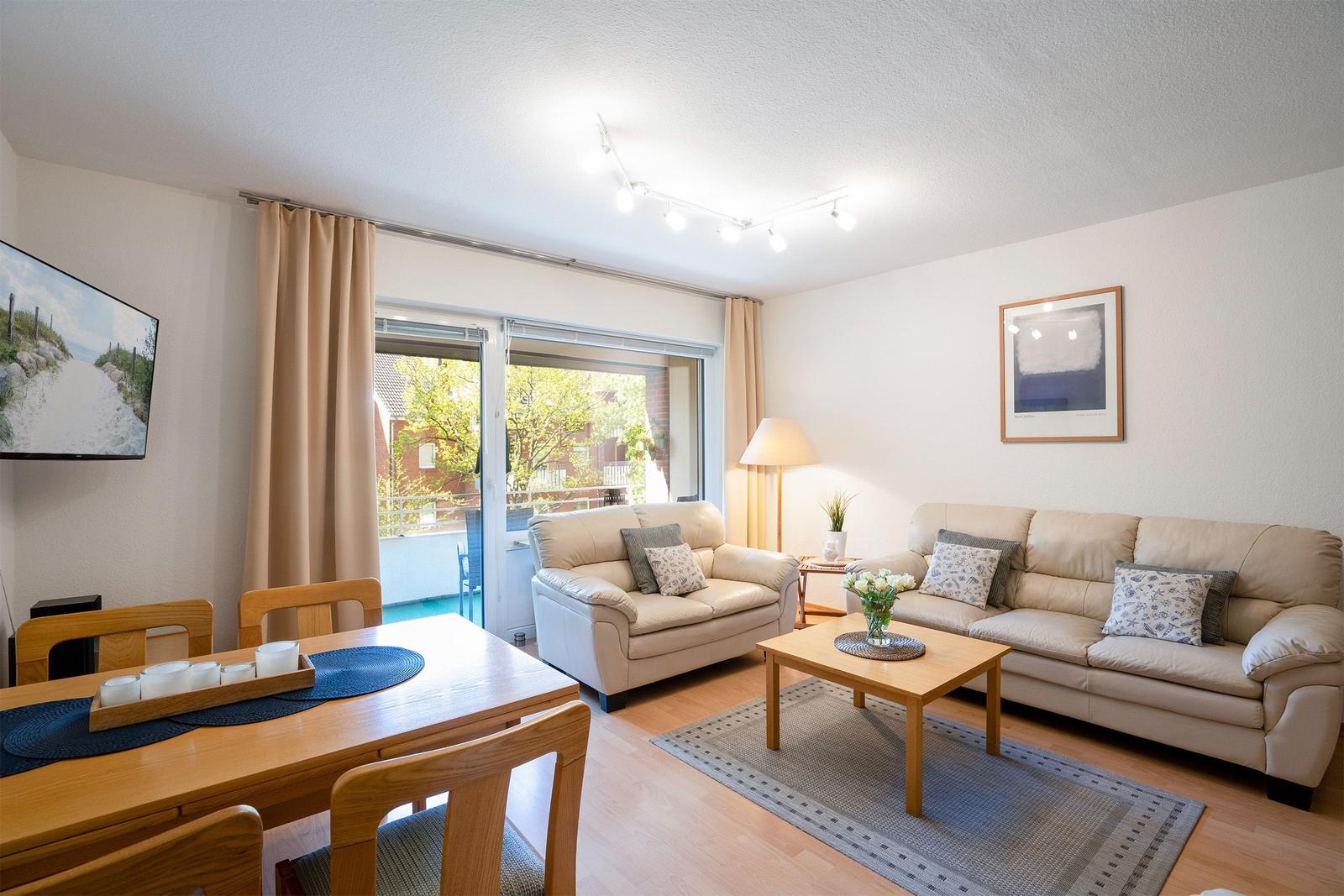Ein Wohnzimmer mit zwei Sofas, einem Tisch und einer Lampe. Auf dem Tisch steht eine Vase mit Blumen.