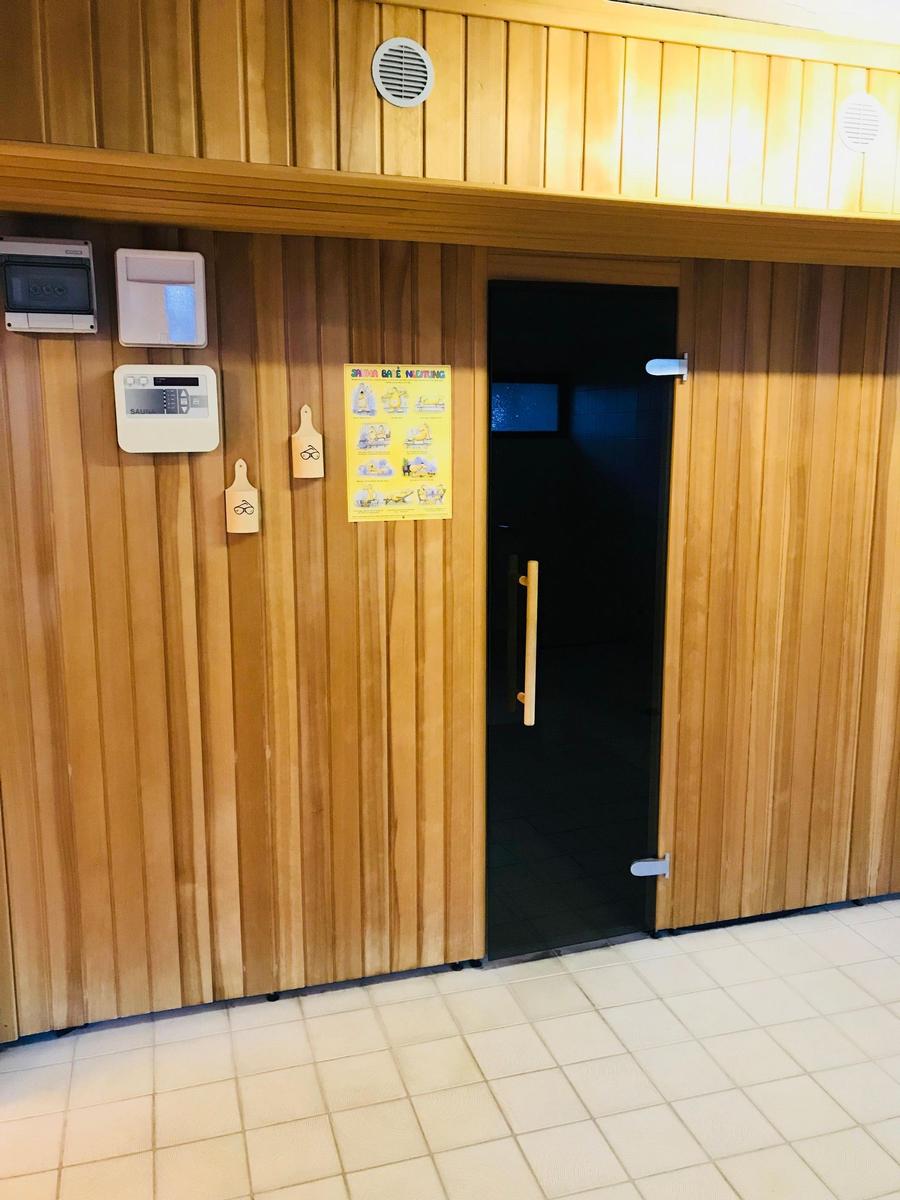 Flur mit Holzboden, Aufzug und moderner Beleuchtung.