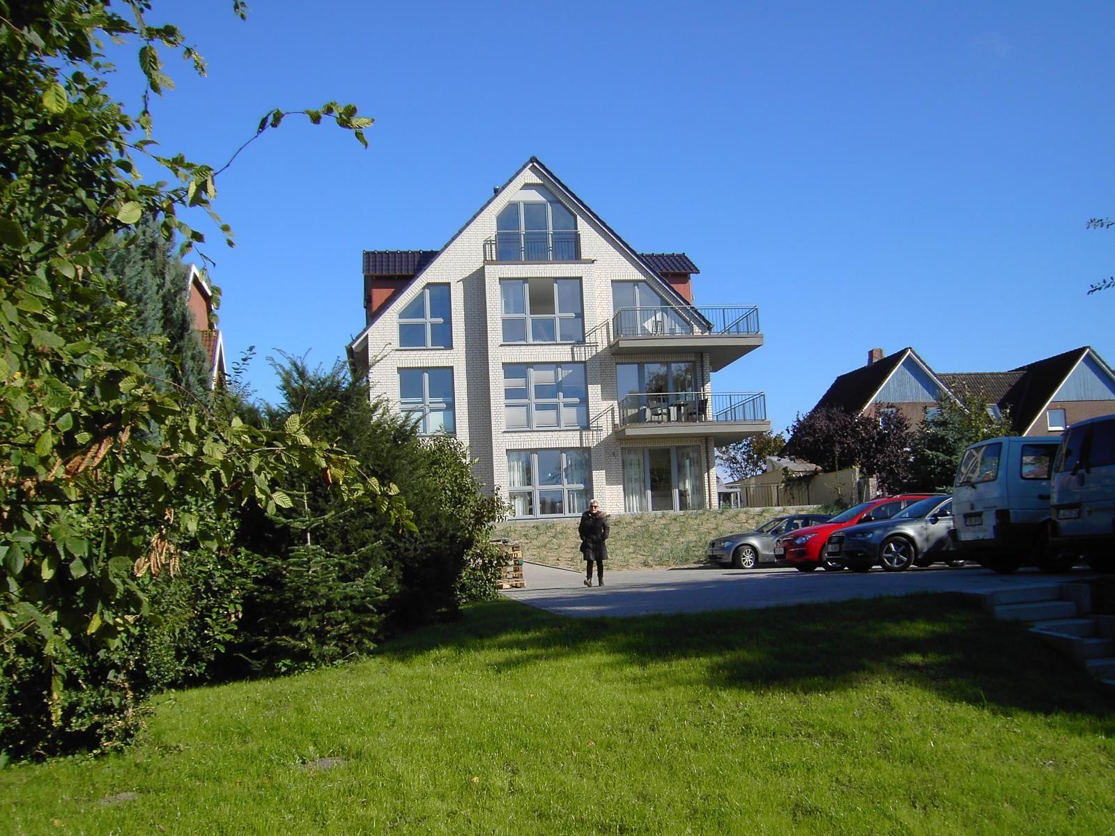 Two cabins with a garden path and trees in the background.