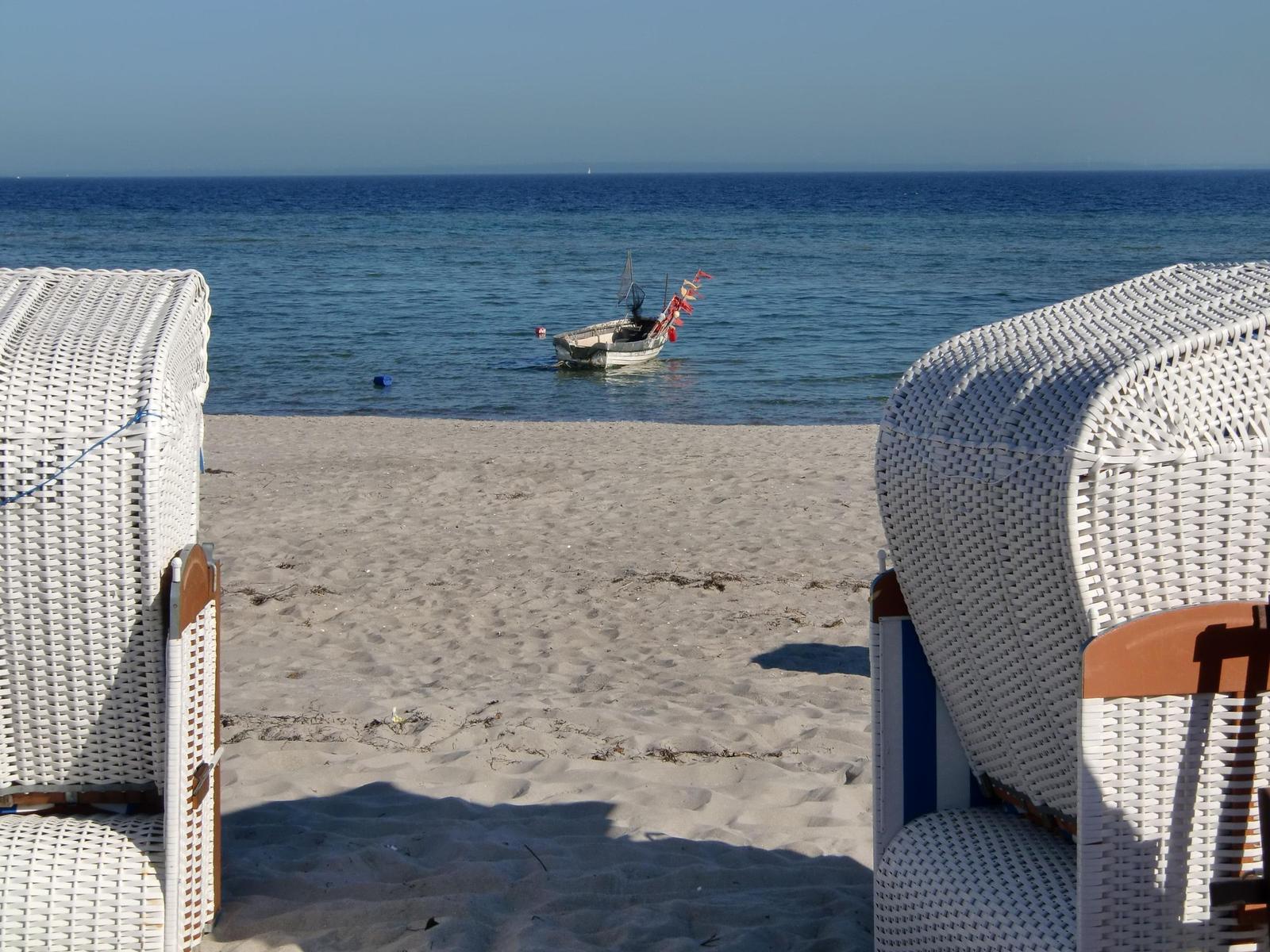 Beach with kite surfers, beach chairs, and a fishing boat.