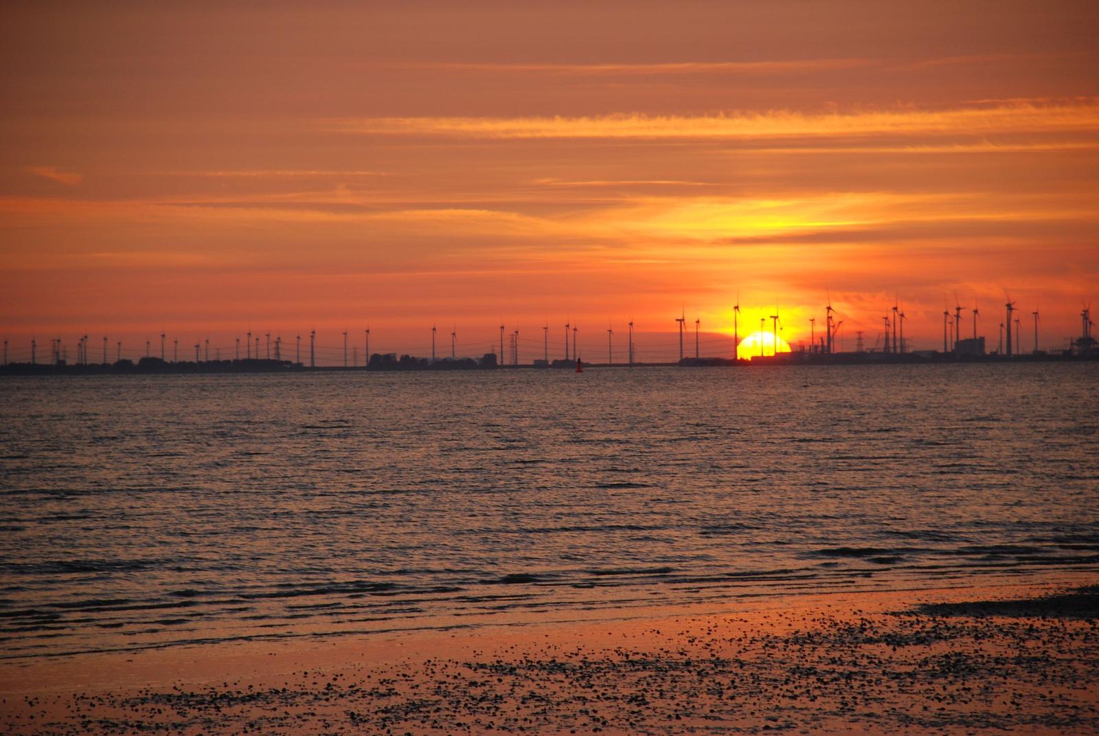 Strand mit Watt und blauem Himmel. Wanderweg und Fahrrad im Vordergrund.