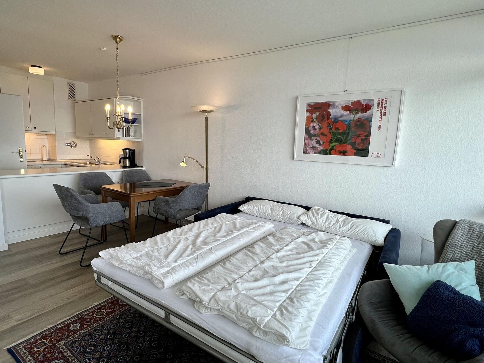 Flur mit Holzboden, Türen und Wandbild. Durchgang zu Schlafzimmer und Wohnbereich mit Blick.