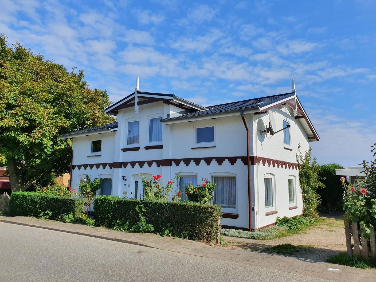 Treppenhaus mit Holzwand und Teppichstufen zum Eingang mit rotem Fliesenboden.