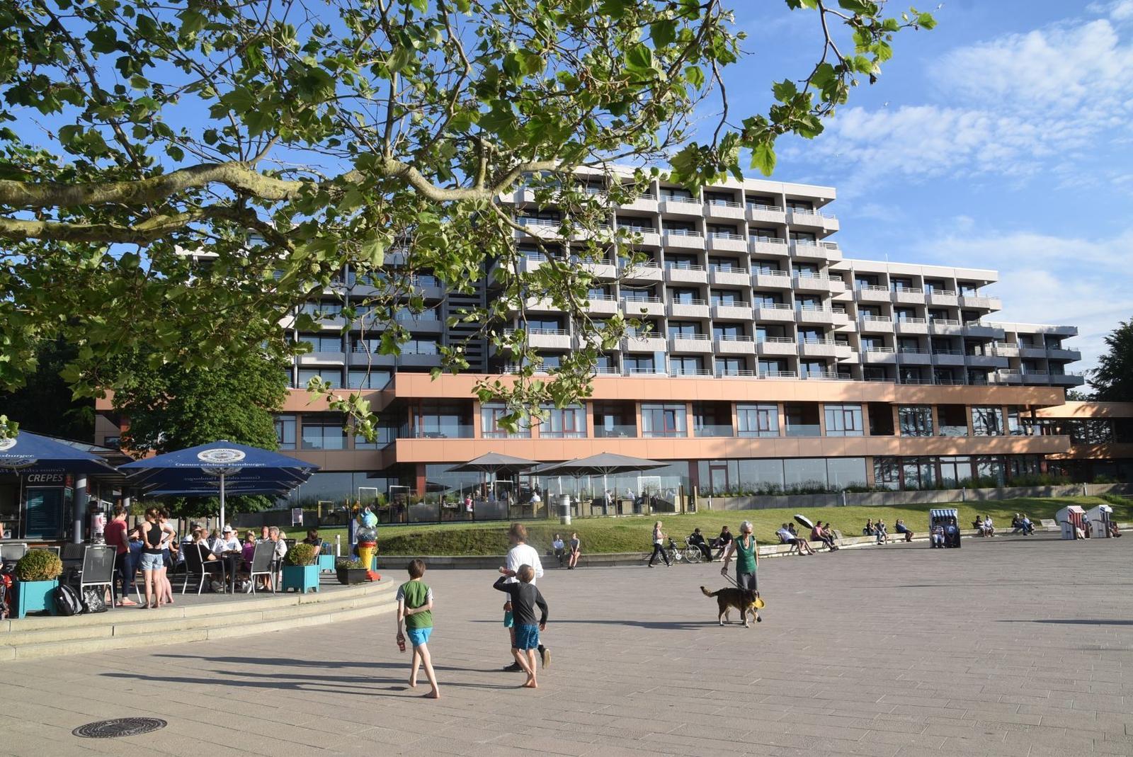 Strandpromenade mit Strand, Fahnen, Strandkorb und Personen