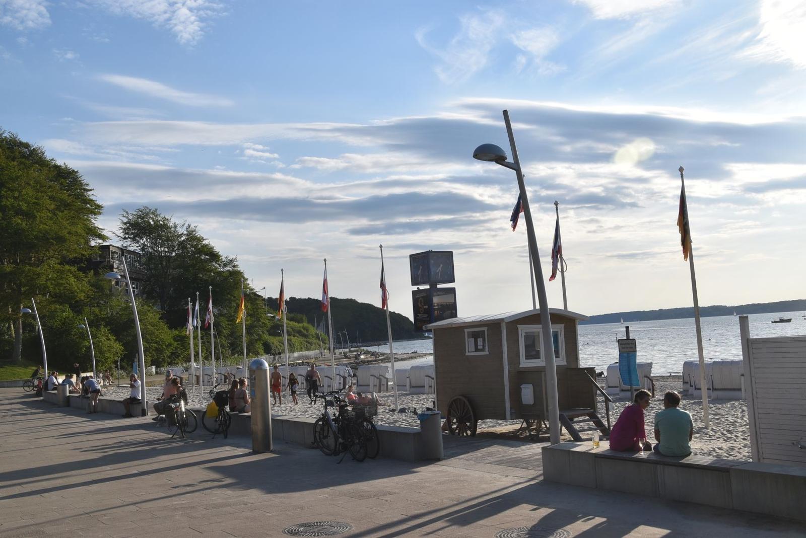 Strand mit Strandkörben, Holzbebauung und Hotel im Hintergrund.