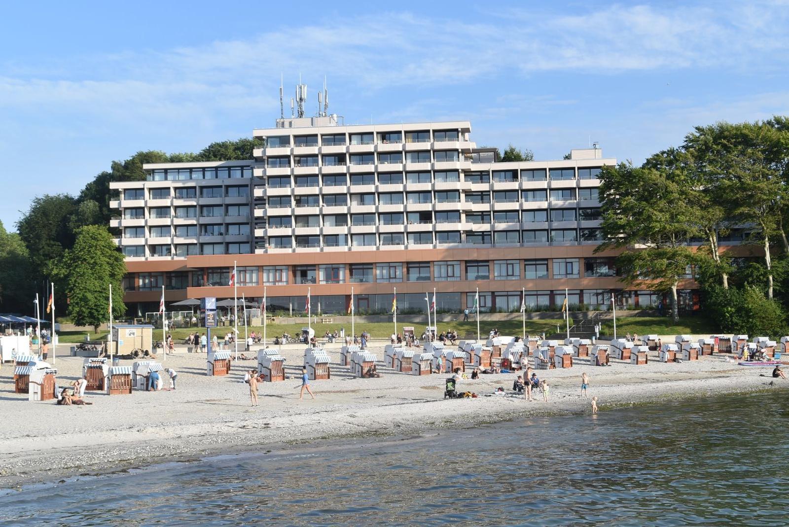 Modernes Gebäude mit Balkonen, Grünfläche, Fahrräder und Sitzbereich im Freien.