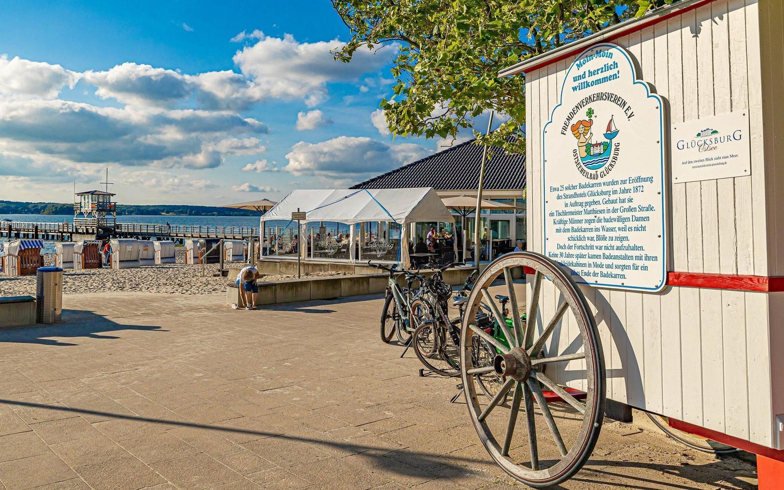 Strand mit Liegestühlen, Steg und Rettungswache am Wasser.