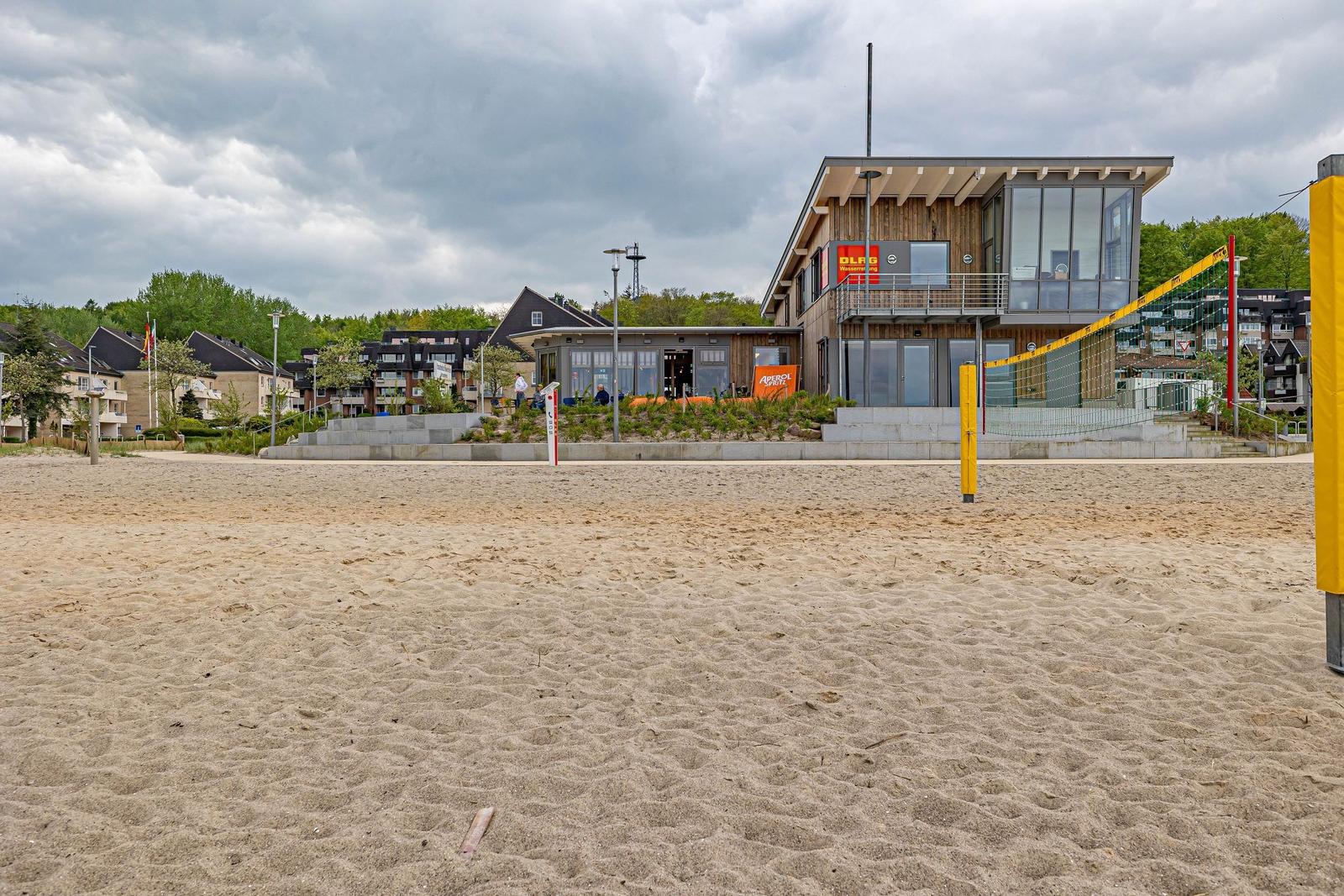 Terrasse mit Tischen und Stühlen vor einem Gebäude am Wasser