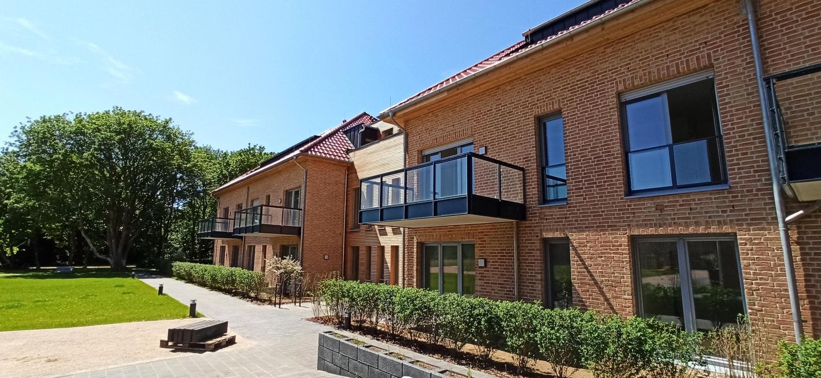 Ein gepflegter Garten mit Wegen, Bäumen und Gebäuden unter blauem Himmel.