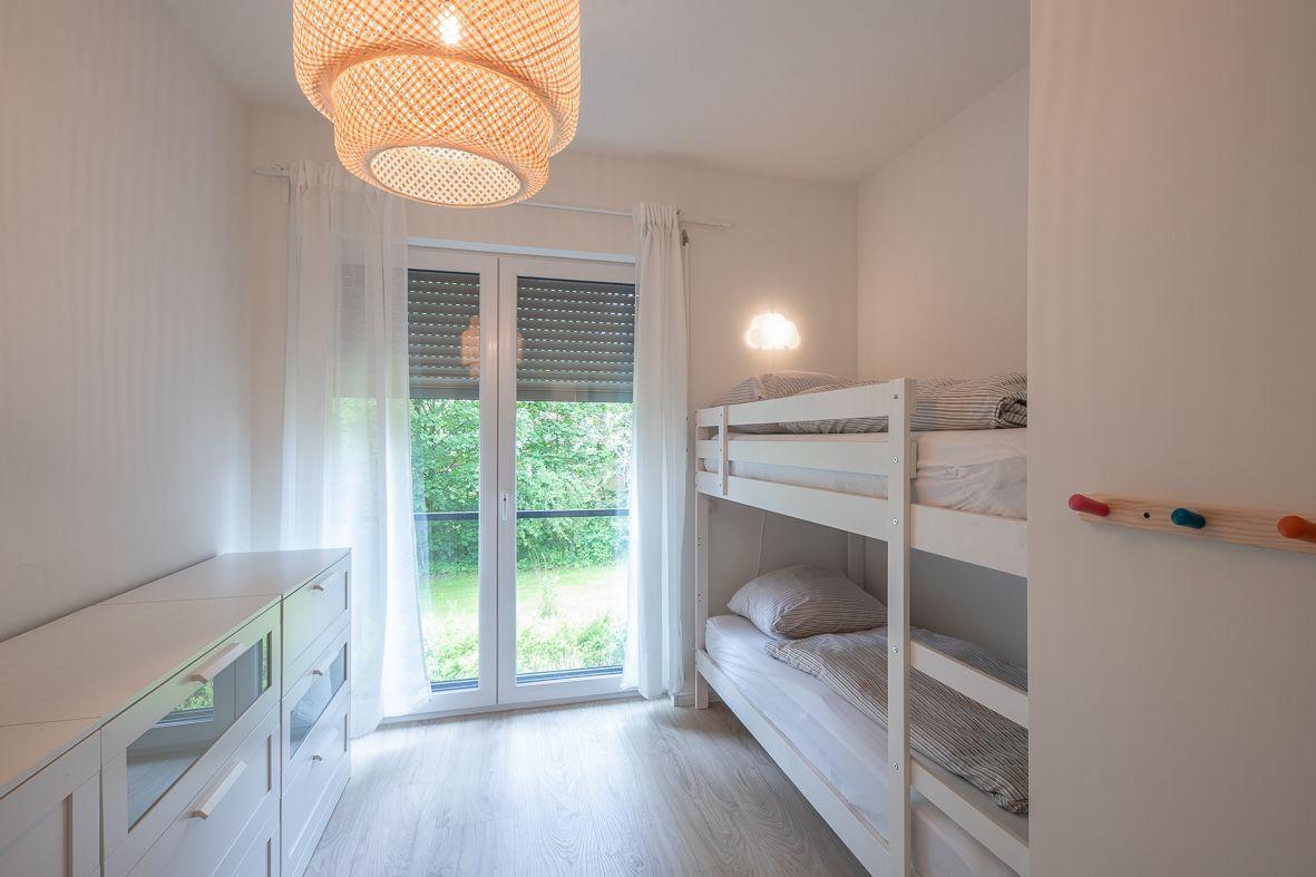 Badezimmer mit Dusche, Waschbecken und Spiegelschrank. Blaue Handtücher und Holzbehälter.
