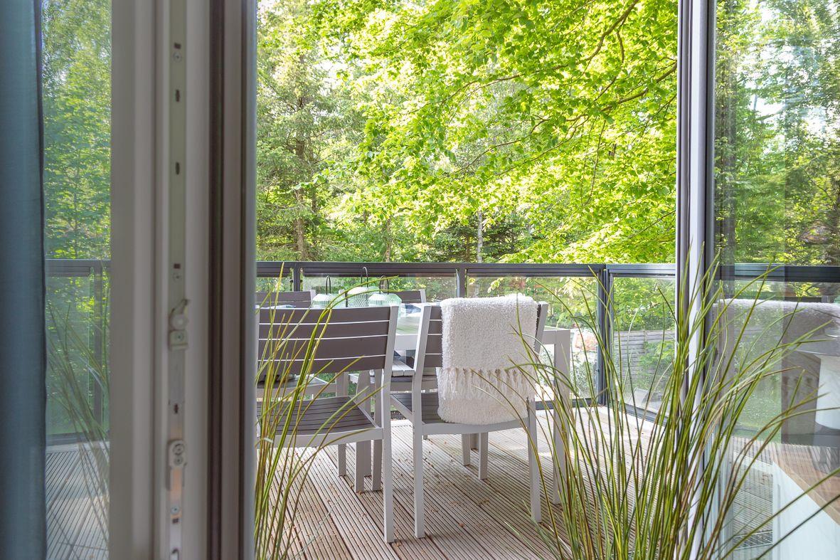 Wohnzimmer mit Sofa, Fernseher und Balkon. Holztisch und Stühle sind vorhanden.