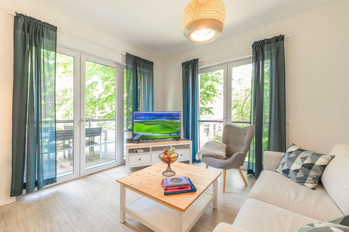 Küche mit weißen Schränken, Edelstahlspüle und Fenster zum Balkon.