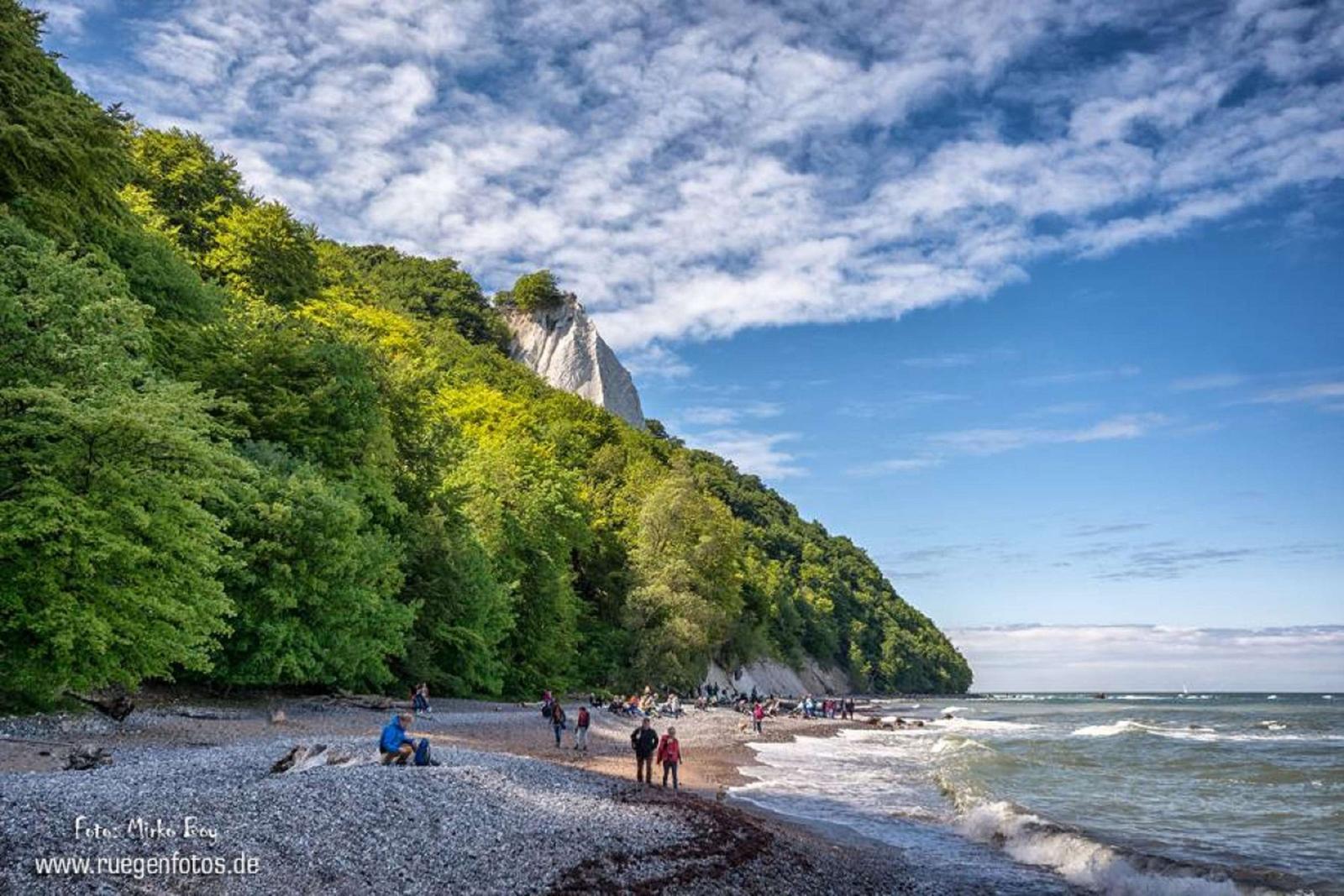 Küstenort mit Steilküste, Strand und Häusern am Meer.