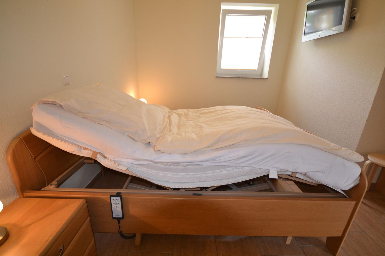 Schlafzimmer mit Doppelbett, Fernseher und Nachttisch