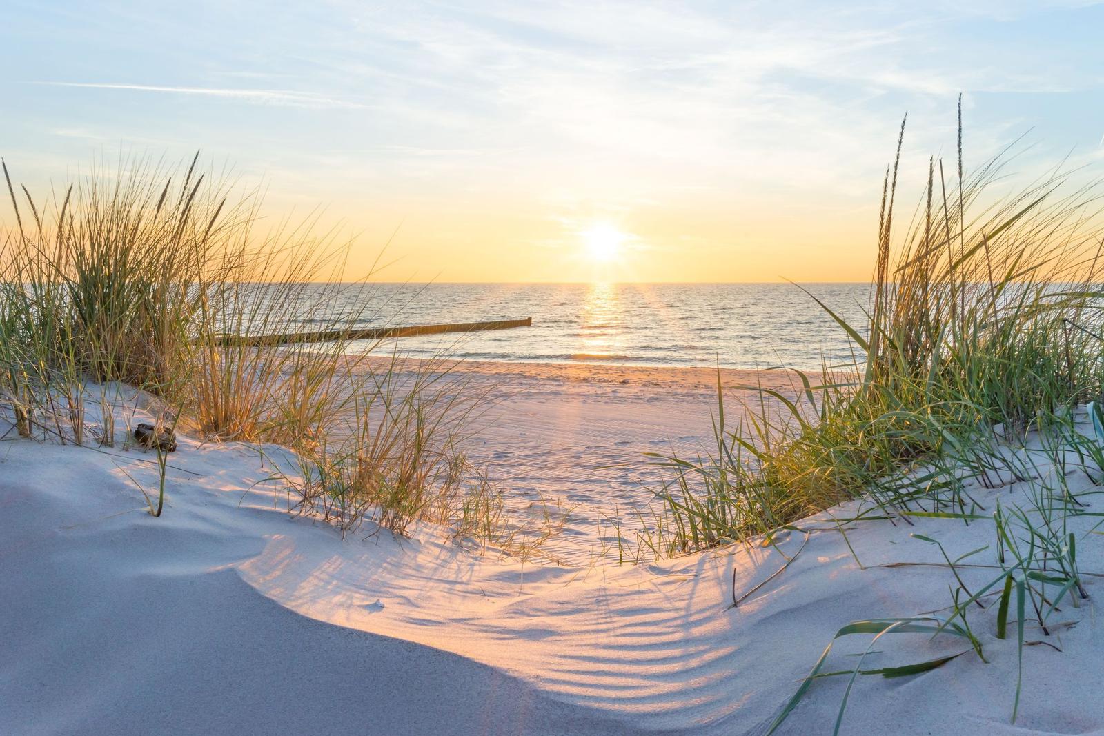 Strand mit Strandkörben und Steg bei Sonnenuntergang