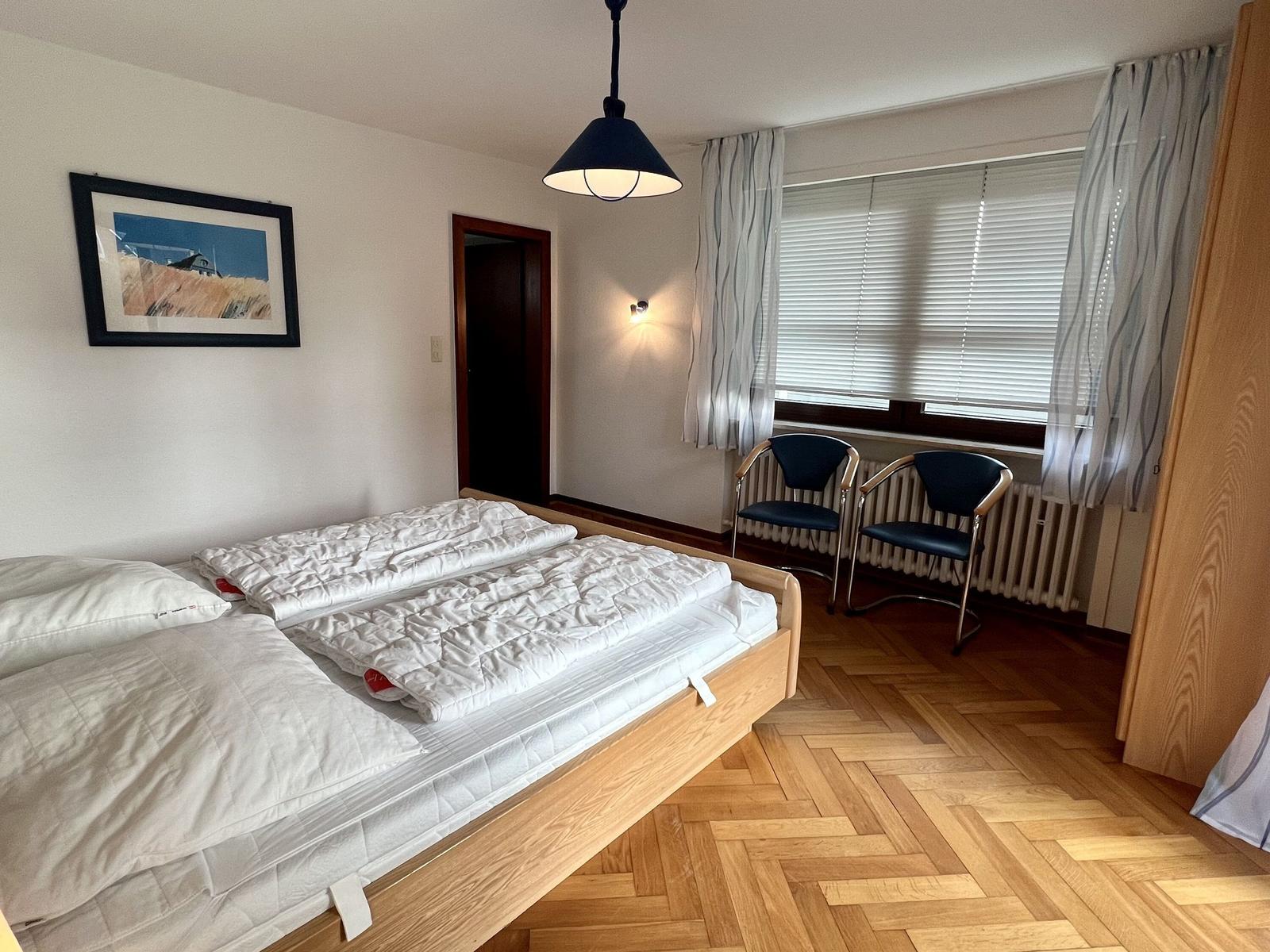 Schlafzimmer mit Doppelbett, Kleiderschrank, TV und Balkontür.