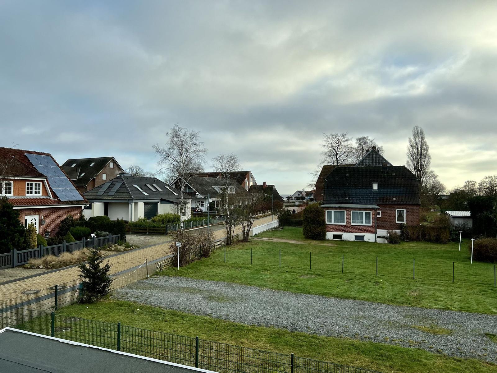 Zweistöckiges Haus mit Balkon, Garten und Terrasse mit Tisch und Stühlen.