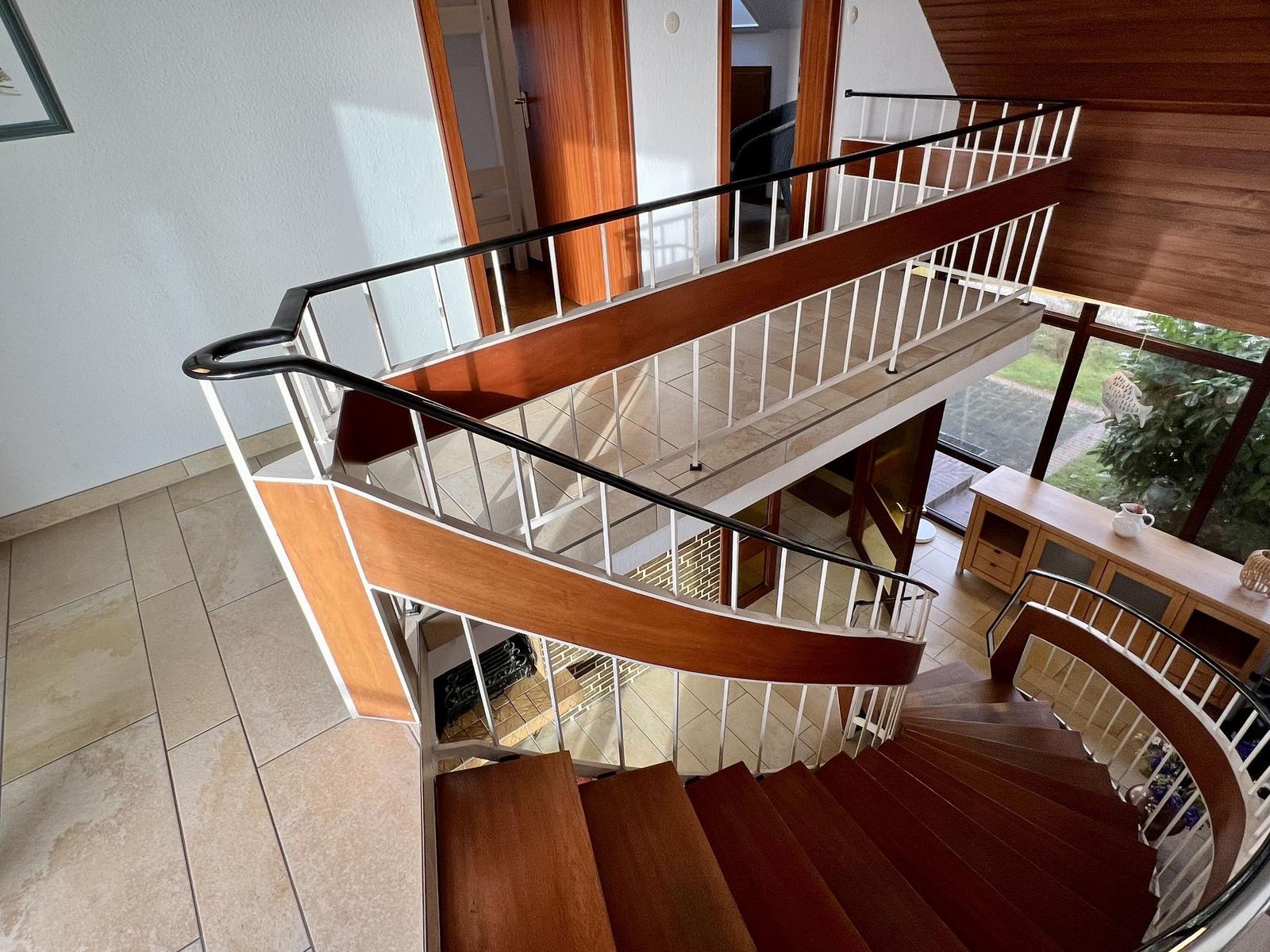 Hausflur mit Treppe, offener Balkon und Türen zu Räumen.