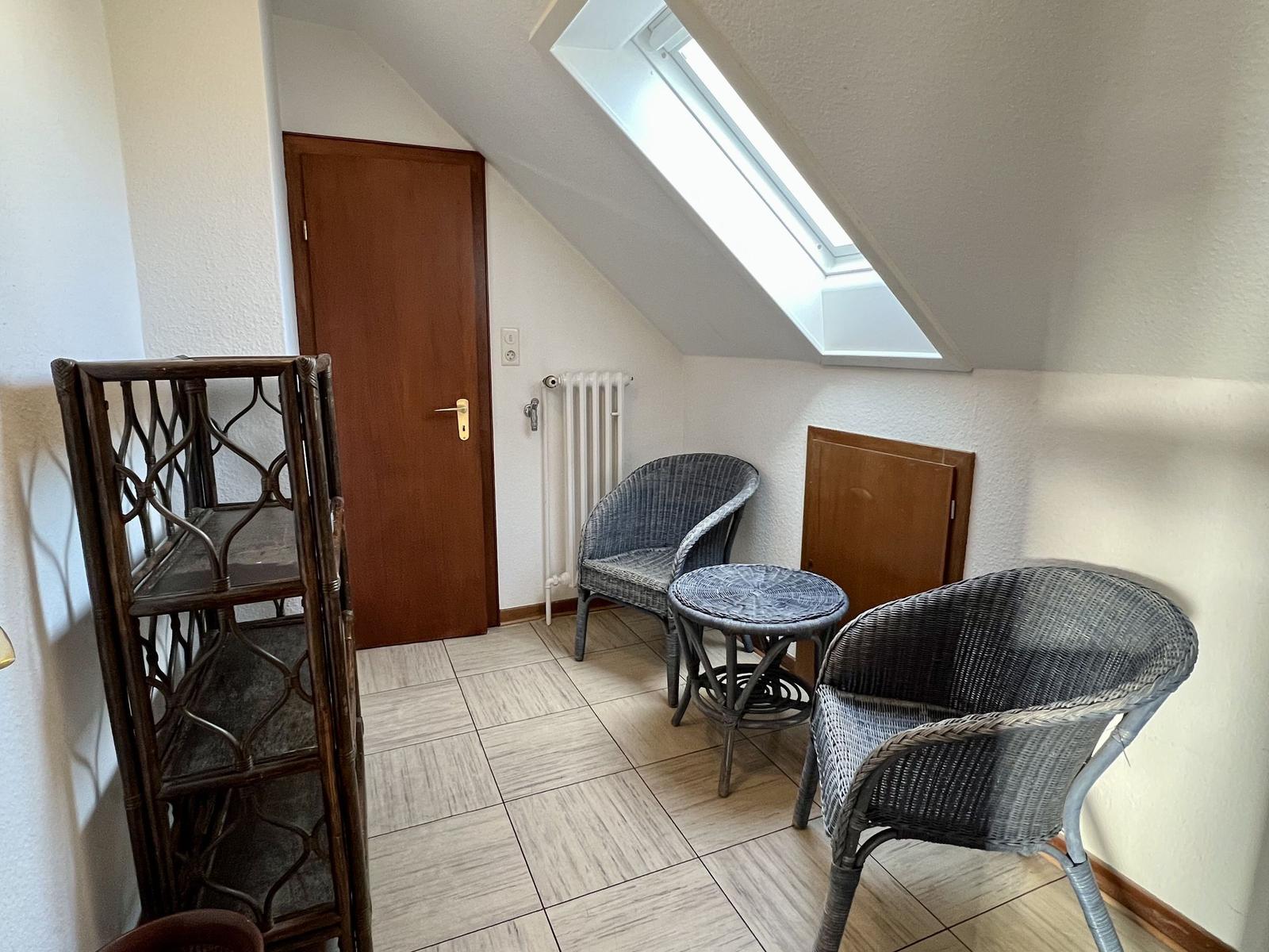 Schlafzimmer mit Doppelbett, zwei Stühlen und Holzboden.