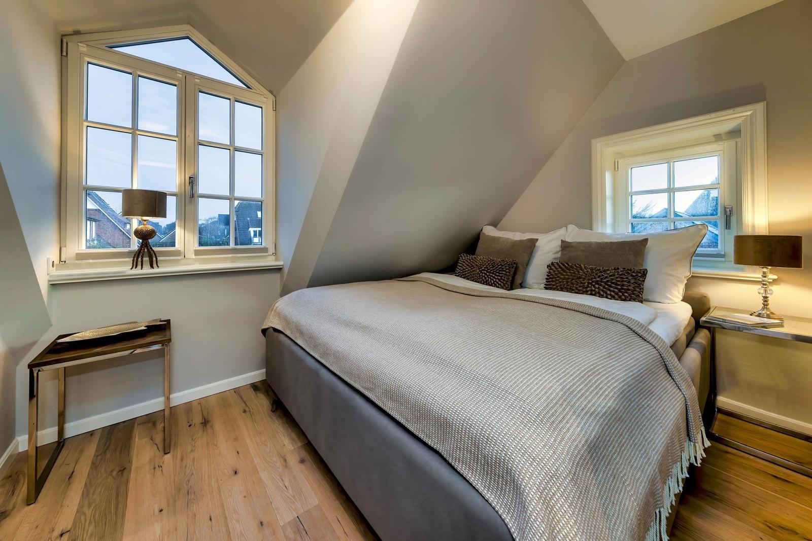 Schlafzimmer mit Dachschräge, Fenster, Bett, Schrank und Beistelltisch.