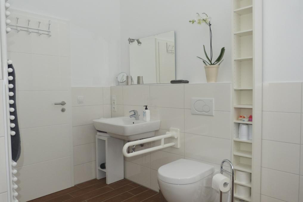 Holztreppe führt zur oberen Etage. Küche und Eingangsbereich sind sichtbar.