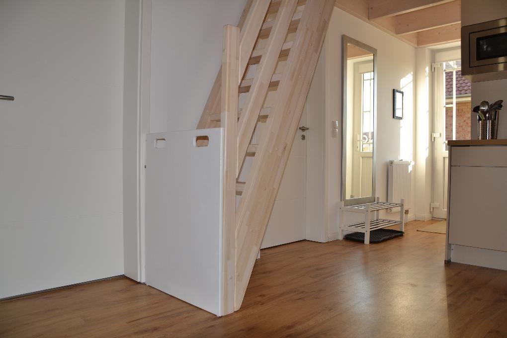 Holzgeländer mit vertikalen Stäben, dunkler Teppichboden und weiße Wände.