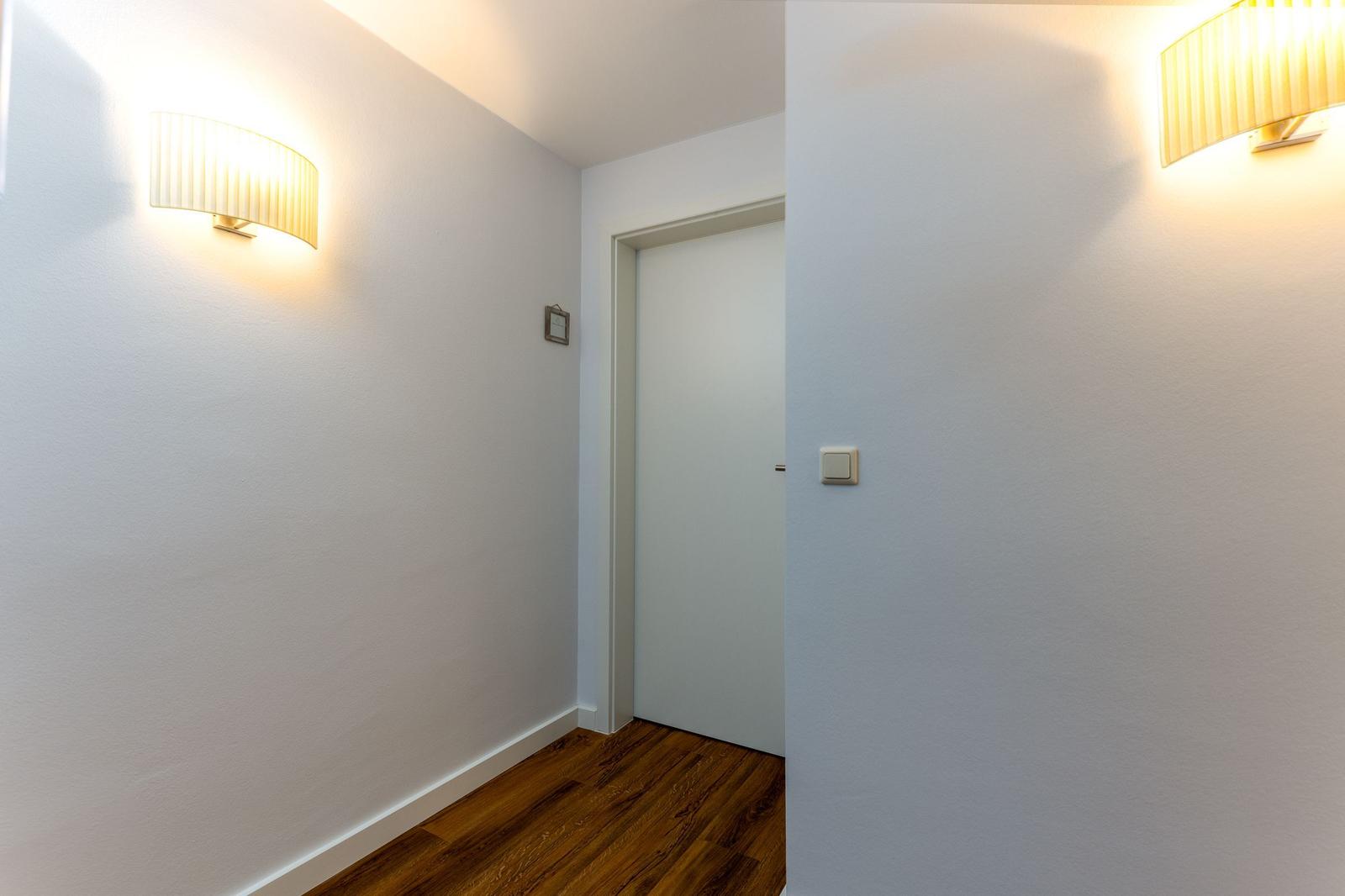 Wohnbereich mit Ledersofa, Holzboden und großem Fenster.